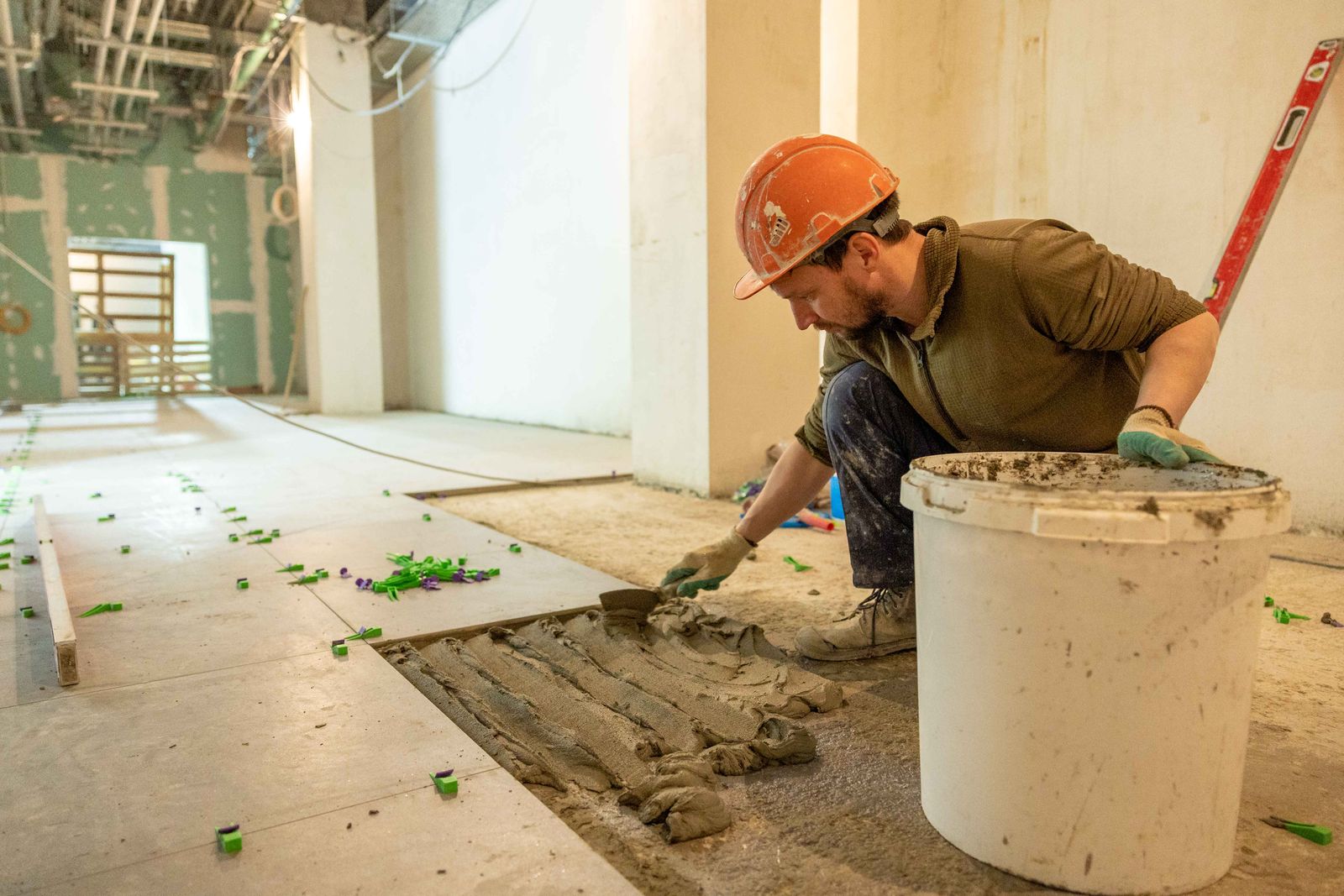 Handwerker verlegt konzentriert großformatige Fliesen bei einer Wohnungsrenovierung