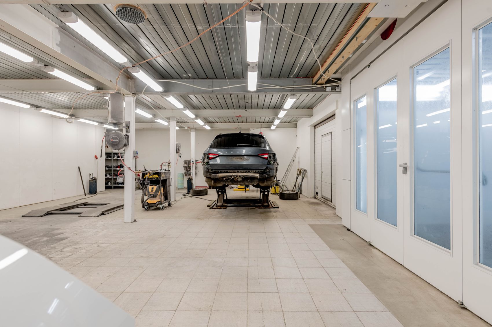 Helle, moderne Kfz-Werkstatt mit Fahrzeug auf der Hebebühne